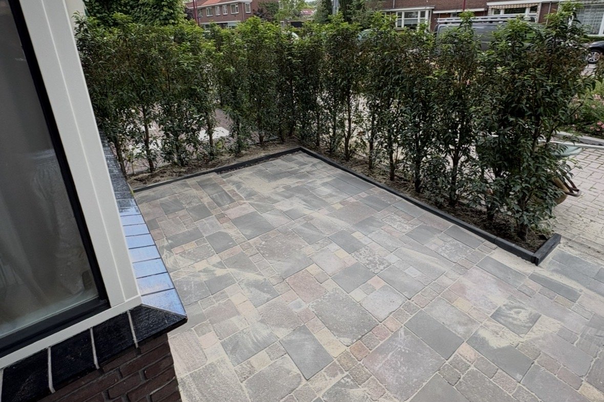 Na: nieuwe bestrating met een haag van nieuwe planten